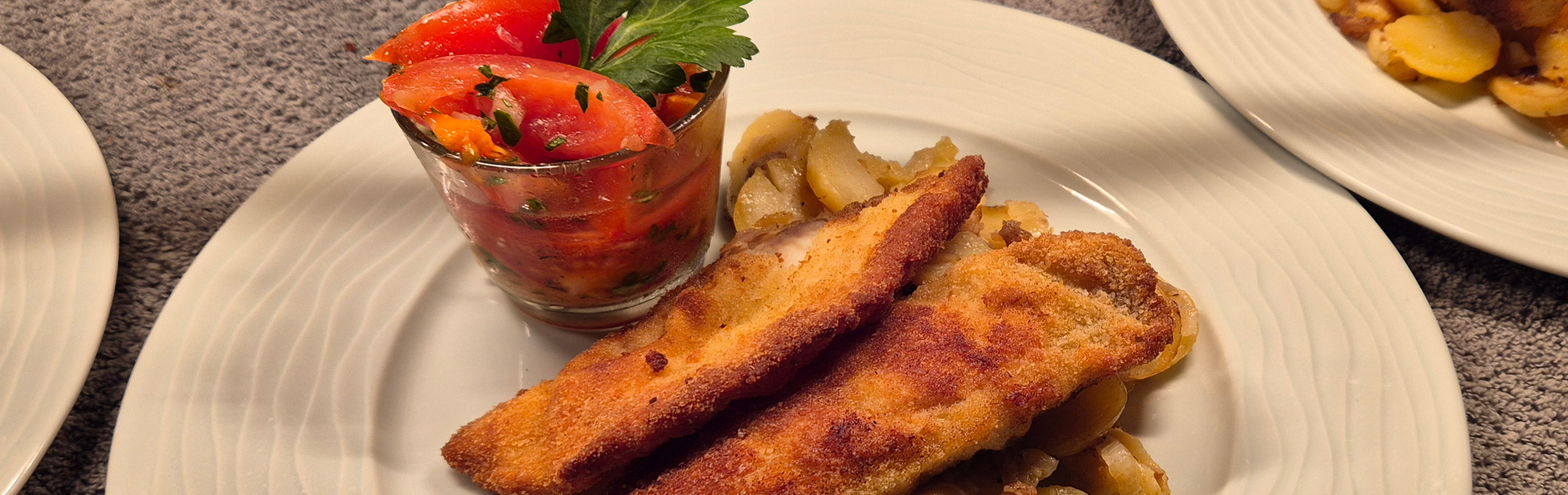 Paniertes Fischfilet mit Bratkartoffeln und Tomatensalat