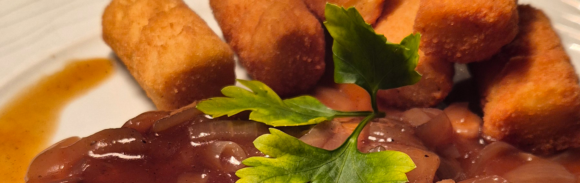 Zwiebelsteak von Schweinerücken mit hausgemachter Zwiebelsoße und Kroketten