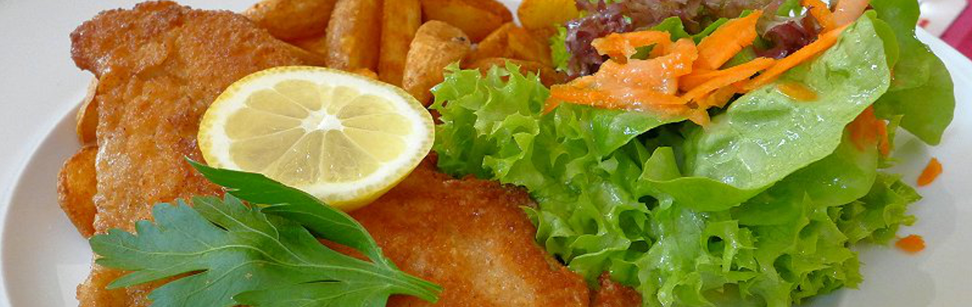 Paniertes Welsfilet mit Kartoffelecken und kleinem Salatbouquet