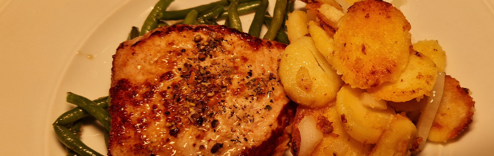 Schweinerückensteak auf Thymianbohnen und Bratkartoffeln